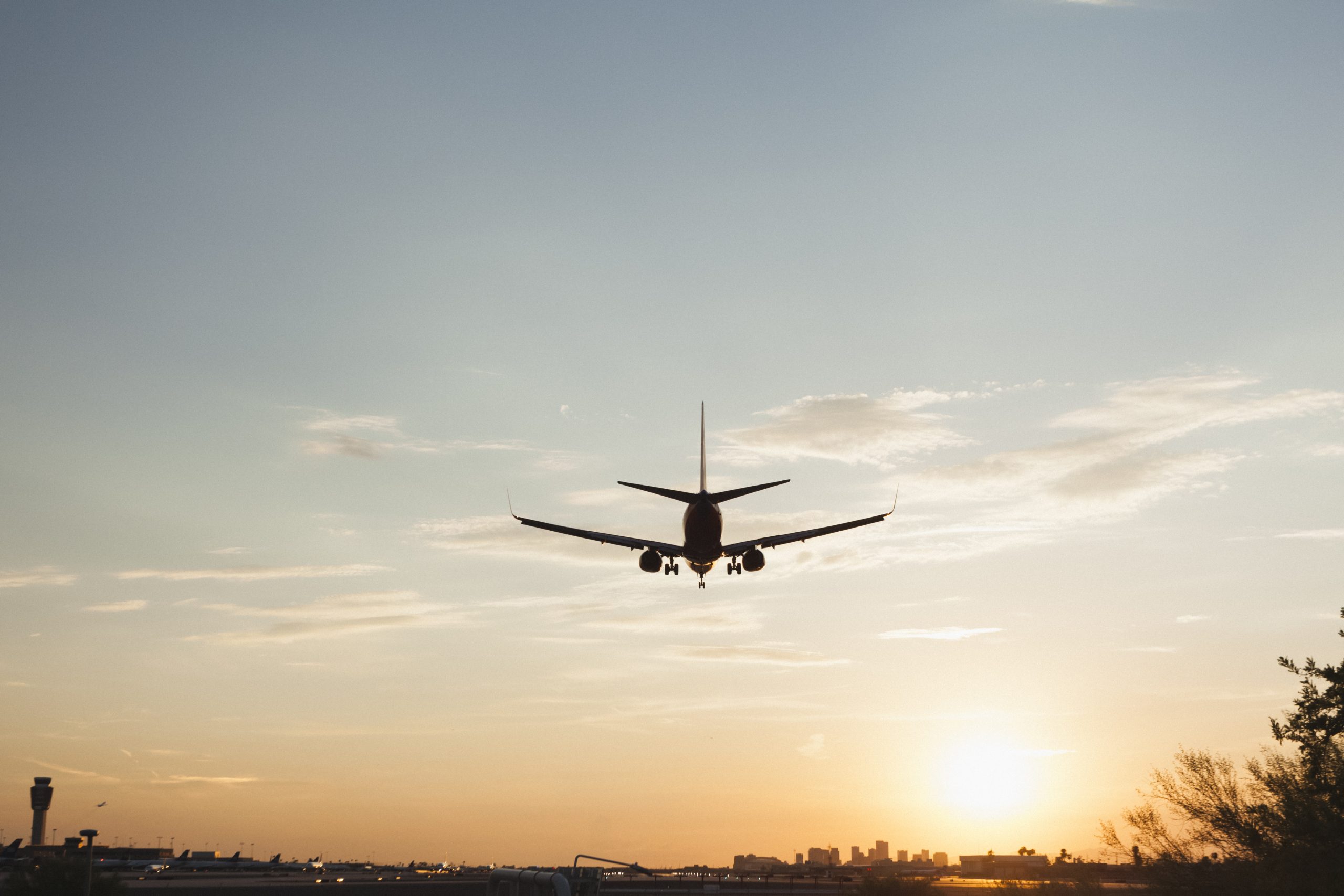 Plane flying into Phoenix Sky Harbor Airport with sun setting in background